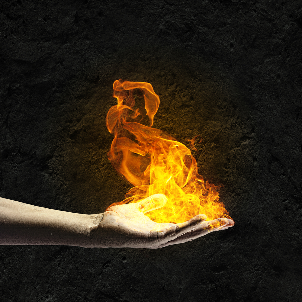 Close up of human hand holding fire flame